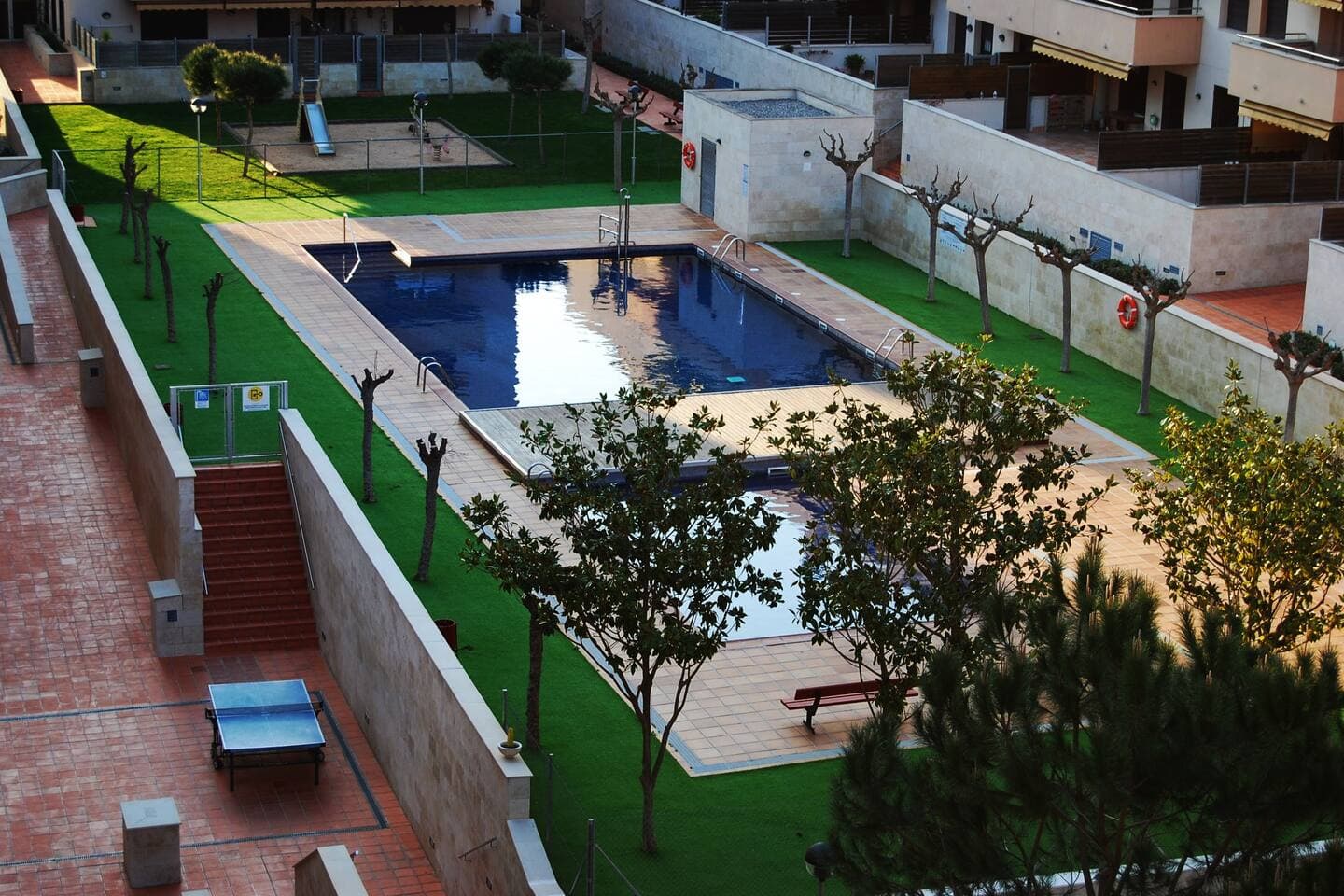 Fenced swimming pool area with sun loungers at our family-friendly penthouse in Fenals